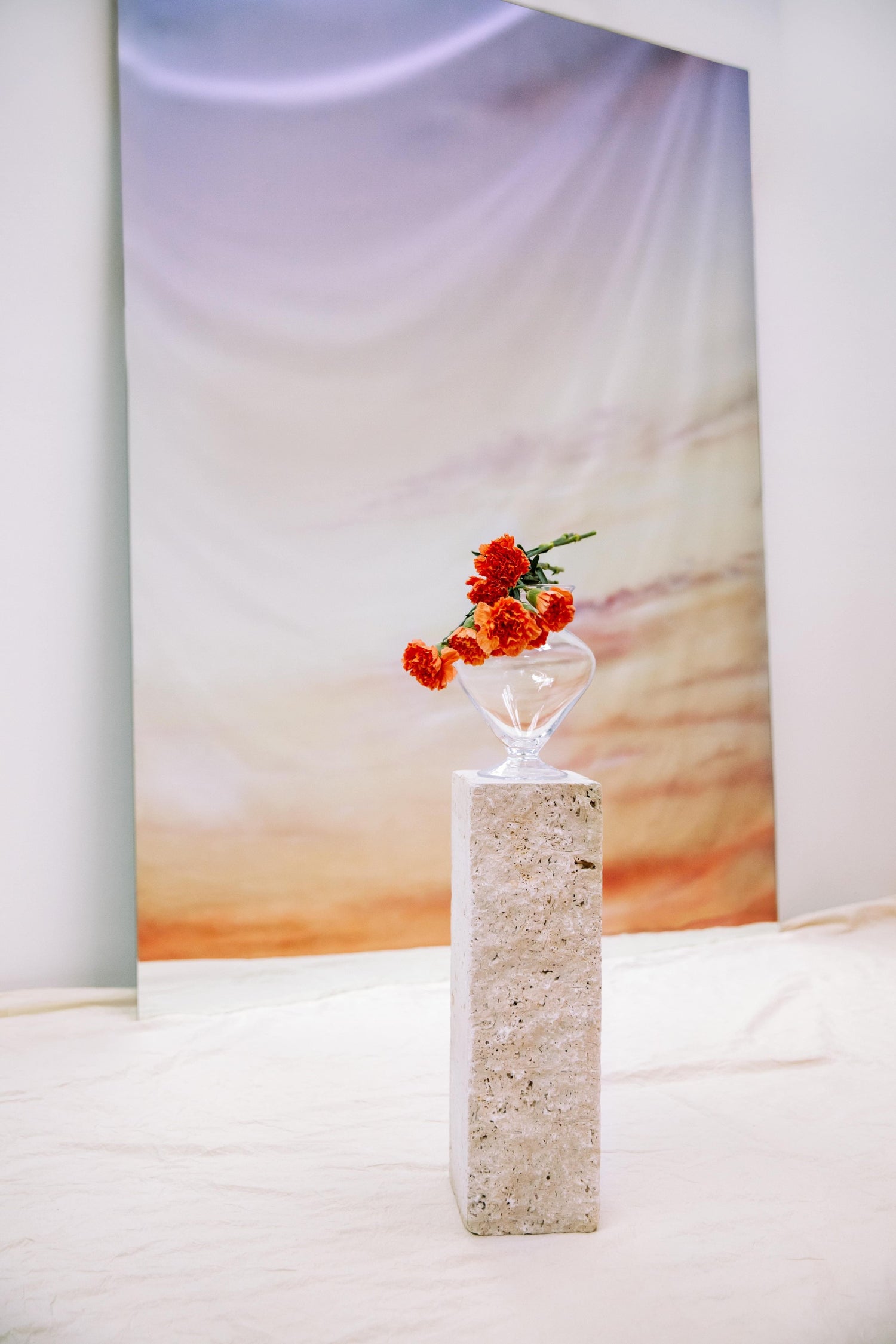 Eine Vase mit Blumen steht auf einer Säule. Im Hintergrund ist ein Spiegel zu sehen.